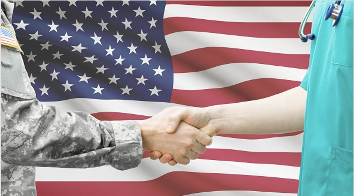 Military servicemember and healthcare provider shaking hands in front of the American flag
